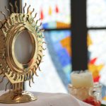 a golden sun - shaped mirror on top of a table next to a candle