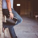 man holding Holy Bible leaning on bricked wall